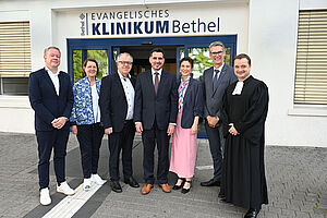 Feierliche Einführung am Evangelischen Klinikum Bethel: Univ.-Prof. Dr. Omid Nikoubashman (Mitte) mit seiner Frau Jenny, wird begrüßt von Pastor Philipp Katzmann, Thorsten Kaatze, Pastor Ulrich Pohl, Petra Krause und Univ.-Prof. Dr. Thomas Vordemvenne (v.r.n.l.).