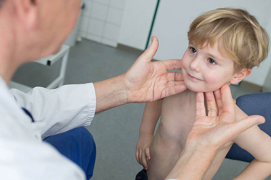 Ein Arzt untersuch einen kleinen Jungen am Hals.