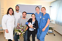 Luca Emanuel fühlt sich bei seiner Mutter Saskia und seinem Vater Tim sichtlich wohl und geborgen. Aylin Yalcin, der Geschäftsführende Oberarzt Ali Alhamwi, Hebamme Sina Wittenbrink und Gesundheits- und Krankenpflegerin Amelie Paulfeuerborn (v.l.n.r.) gratulieren. 