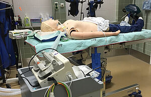 Ein Dummy liegt auf einer Liege. Die Puppe ist intubiert.