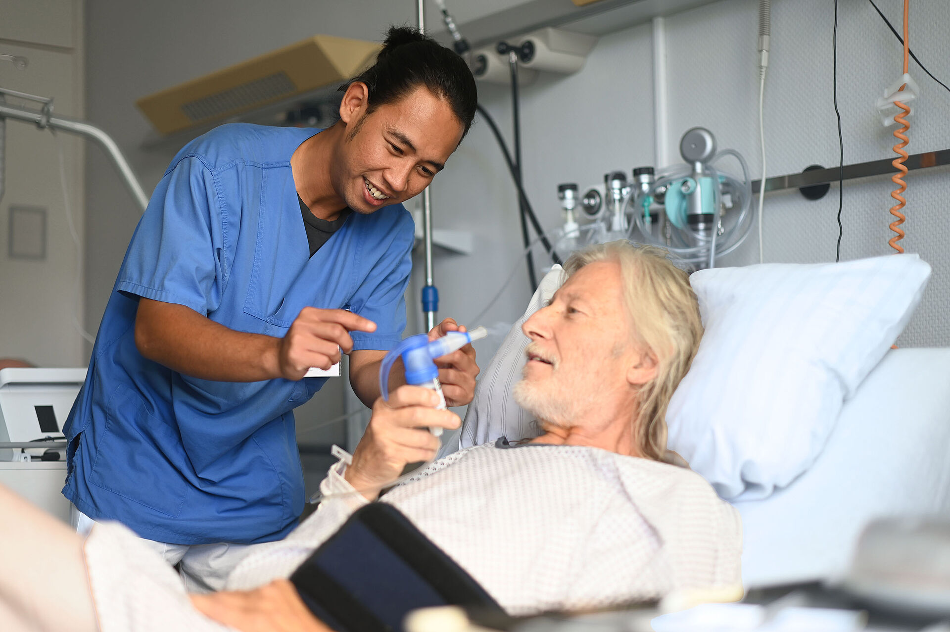 Engagierte Pflege auf der pneumologischen Station: Eine Pflegefachkraft betreut einen Patienten am Bett.