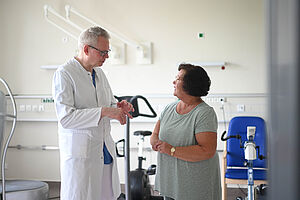 Gespräch zwischen einem Azrt und einer Patientin. Die beiden Personen stehen sich gegenüber.