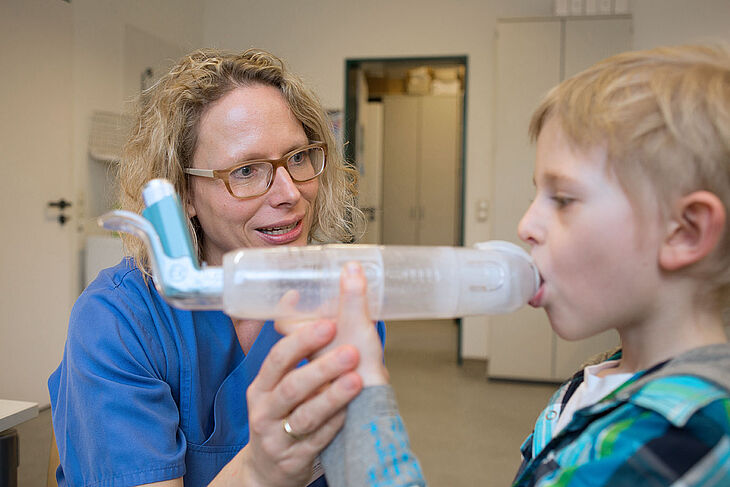 Eine Pflegekraft unterstützt einen Jungen bei der Inhalation.