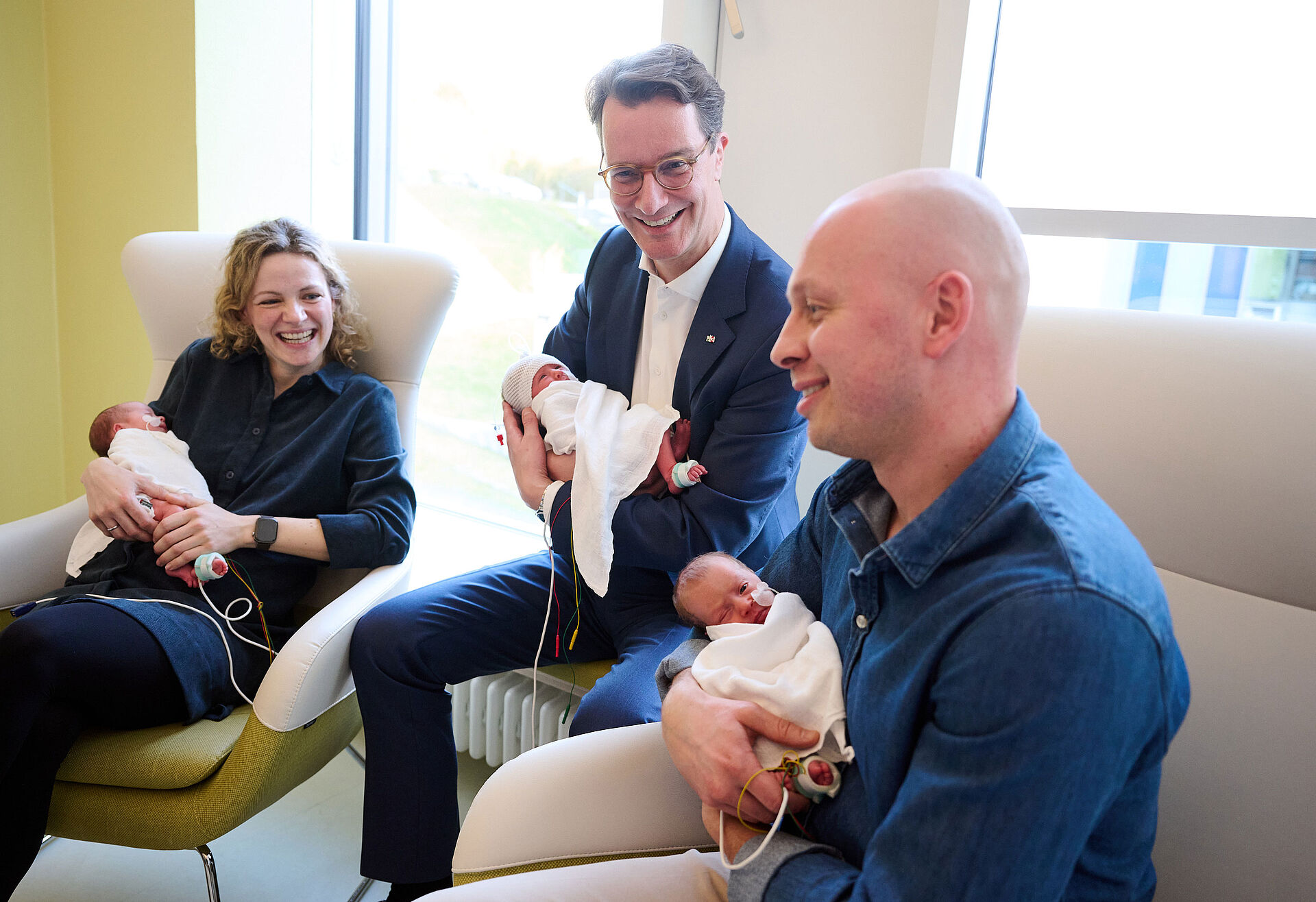 Ministerpräsident Hendrik Wüst mit seinen frischgeborenen Patenkindern Romy, Klara und Jette sowie ihre Eltern Mara und Max Deboer. Foto: Land NRW/Bernd Thissen