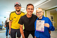 Gruppenfoto: Dennis Altmaier mit Paul und seinem Vater. Paul hält ein Autogramm in seiner Hand.