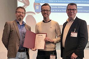 Dink 2019 Drei Männer gucken ins Bild.