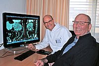 Univ.-Prof. Dr. med. Jan Schulte am Esch und Claus Diekmann, am Rechner im HIntergrund sind Untersuchungsbilder der Leber zu sehen.