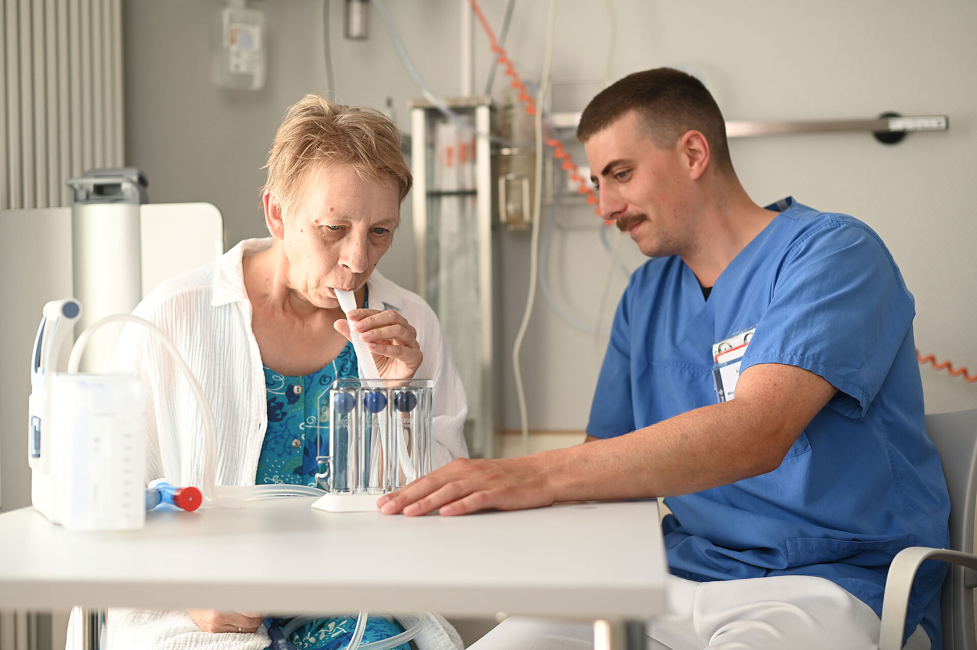Auf der pneumologischen Station steht die Atmung im Mittelpunkt: Eine Pflegefachkraft betreut eine Patientin am Bett.