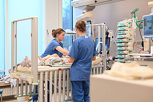 Zwei Kinderkrankenpflegerinnen arbeiten am Patientenbett auf der Kinderintensivstation.