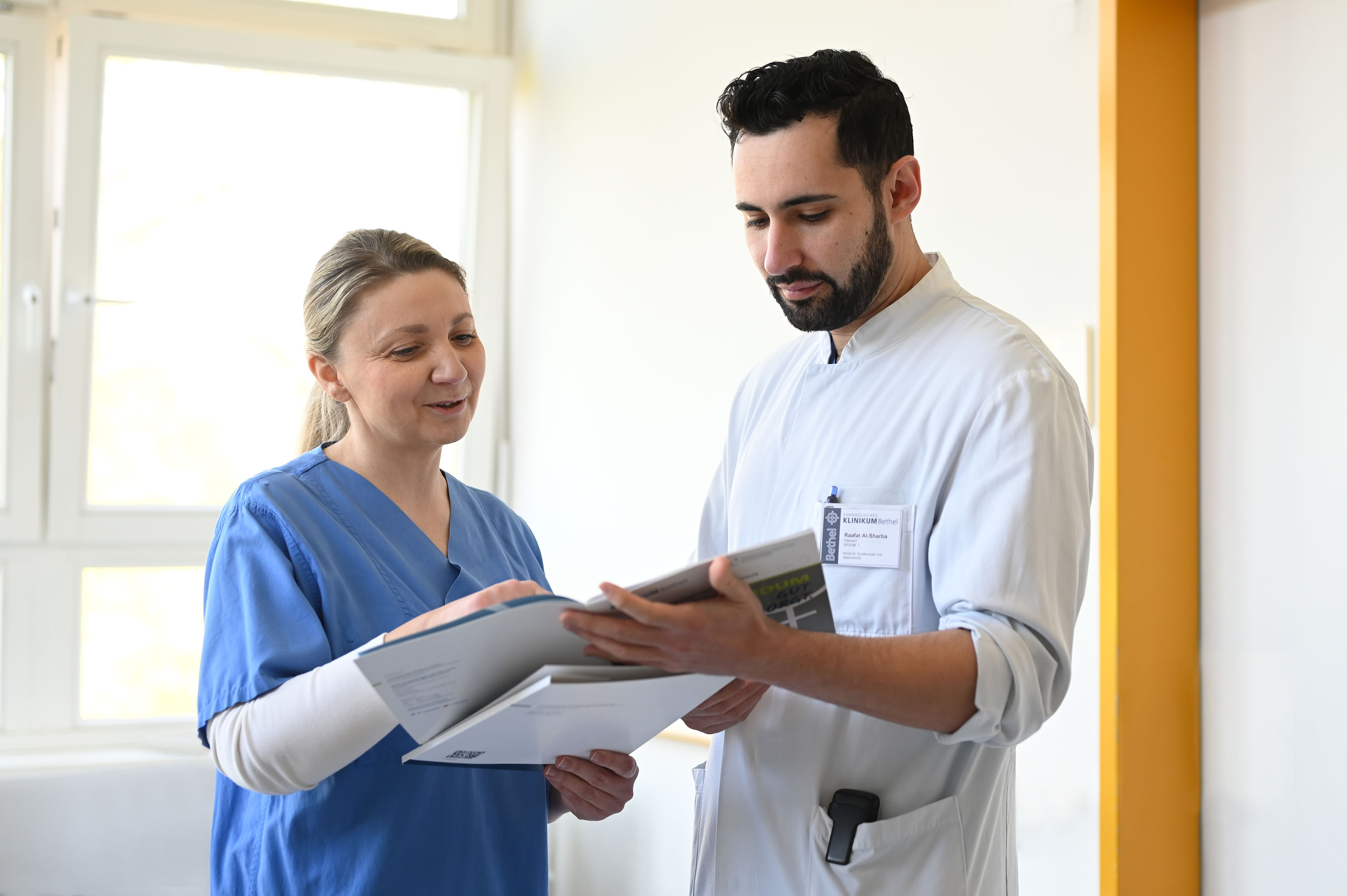 Gespräch zwischen Ärztin und Pflegekraft auf dem Stationsflur.